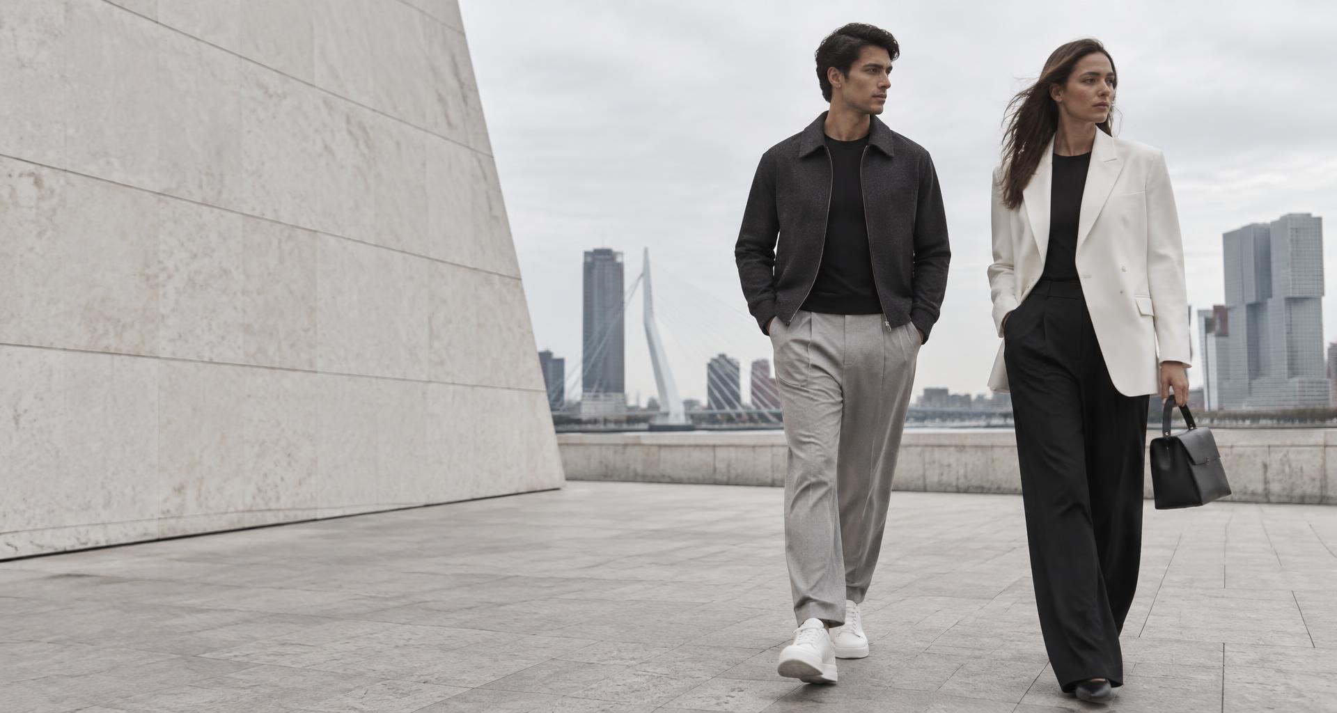 Fashioncampagne met twee modellen in zwart-witte outfits aan de Rotterdamse skyline
